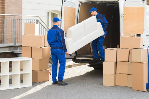 Professional movers carrying furniture from a flat in East London